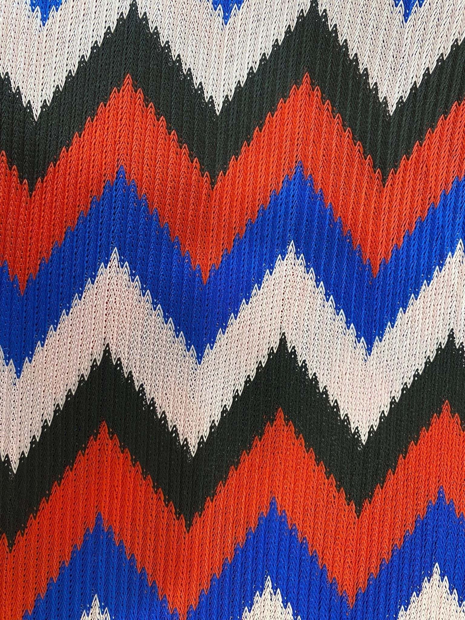 close-up of luxury zigzag knit jersey fabric in blue red black and pink with textured pattern