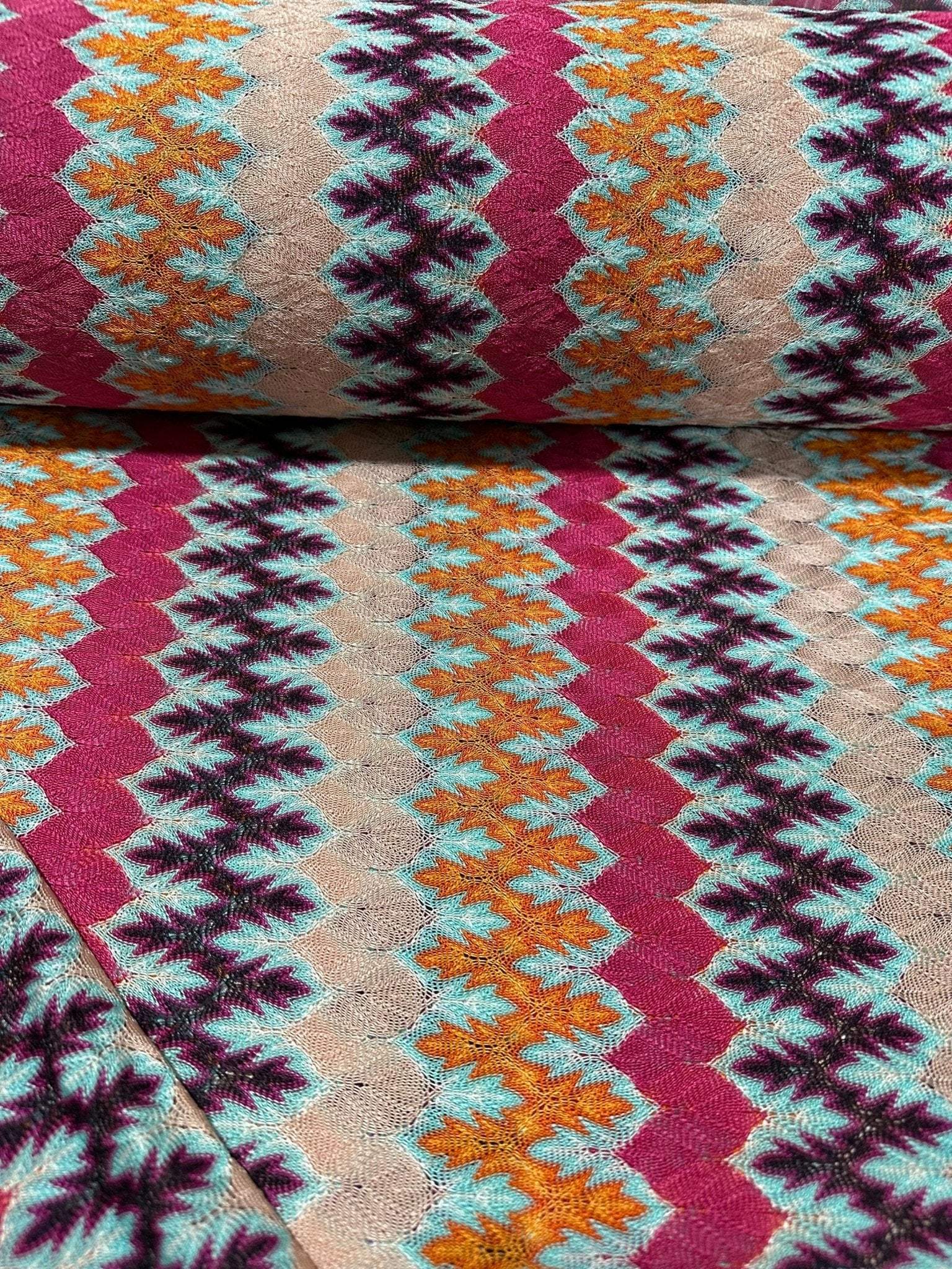 Zigzag Knit Jersey Fabric with multicolor chevron pattern in vibrant hues, soft and breathable knit textile ideal for sewing garments.