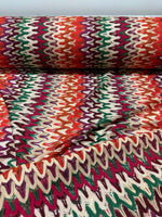 Multicolor zigzag knit jersey fabric with chevron pattern in vibrant red, green, purple, and cream tones, perfect for clothing projects.