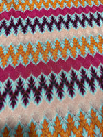 Multicolor zigzag knit jersey fabric with chevron pattern in orange, teal, maroon, and beige tones