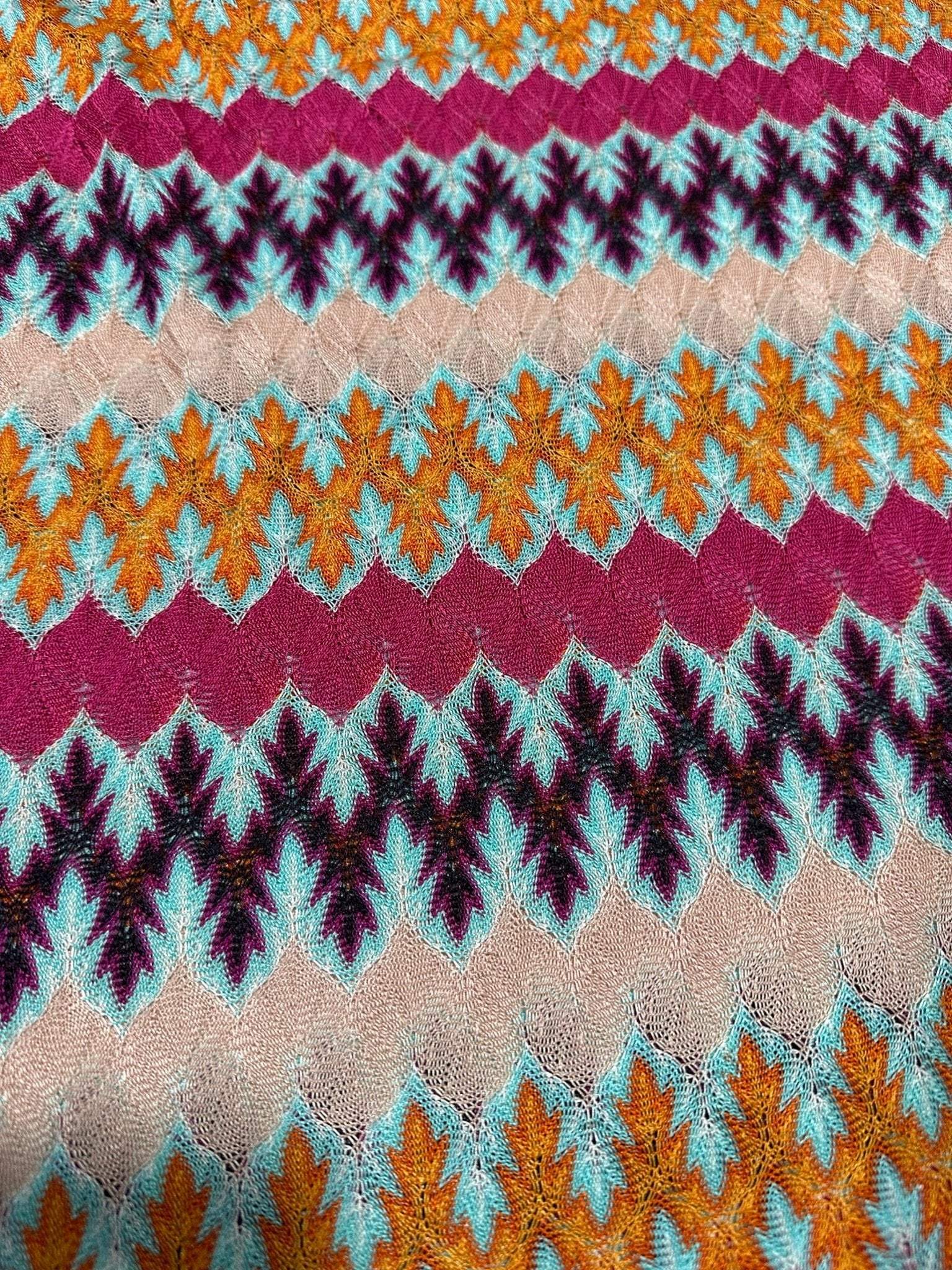 Multicolor zigzag knit jersey fabric with chevron pattern in orange, teal, maroon, and beige tones