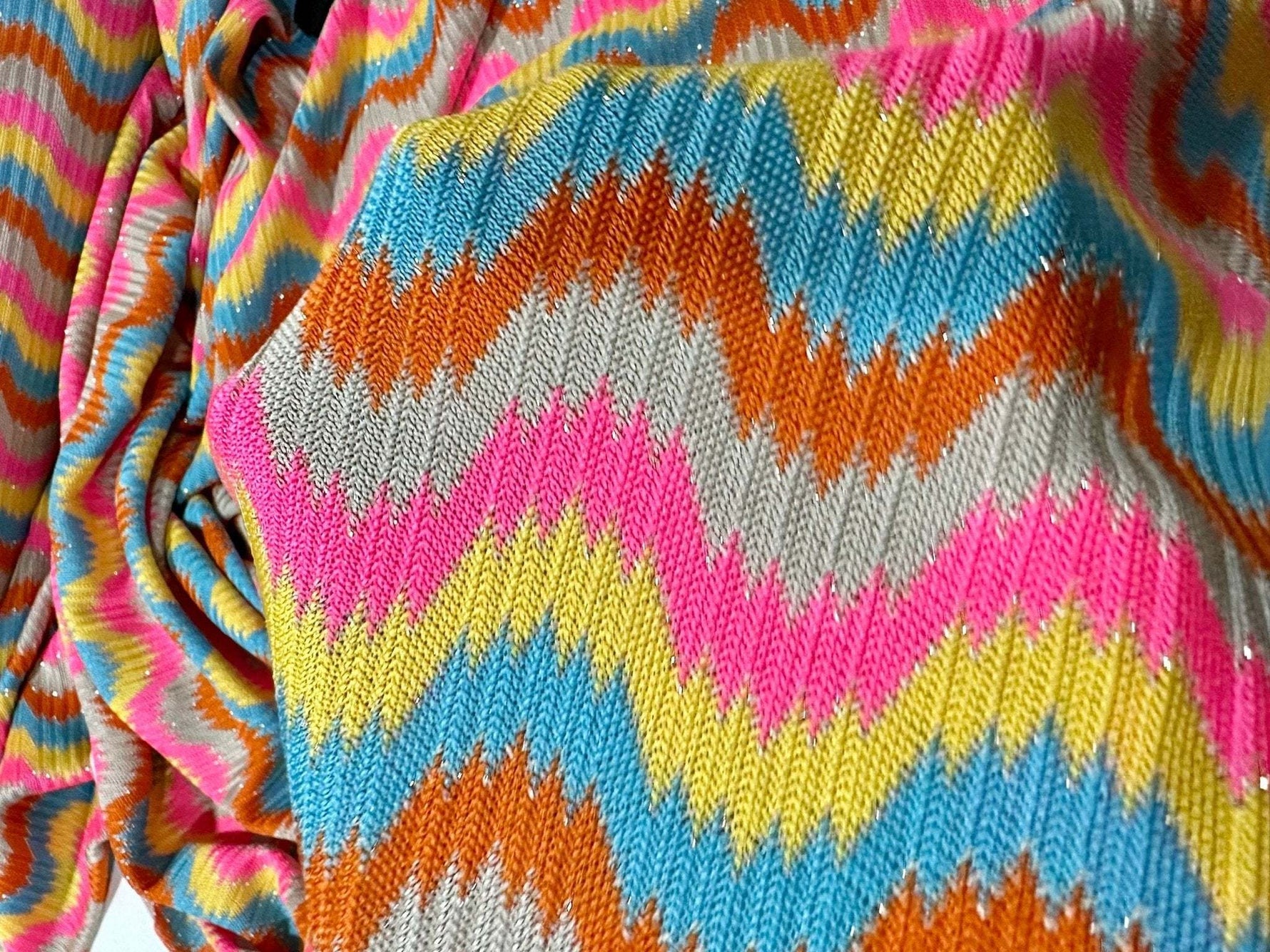 Luxury zigzag knit fabric with vibrant pink, blue, yellow, orange, and gray chevron pattern for stylish clothing projects