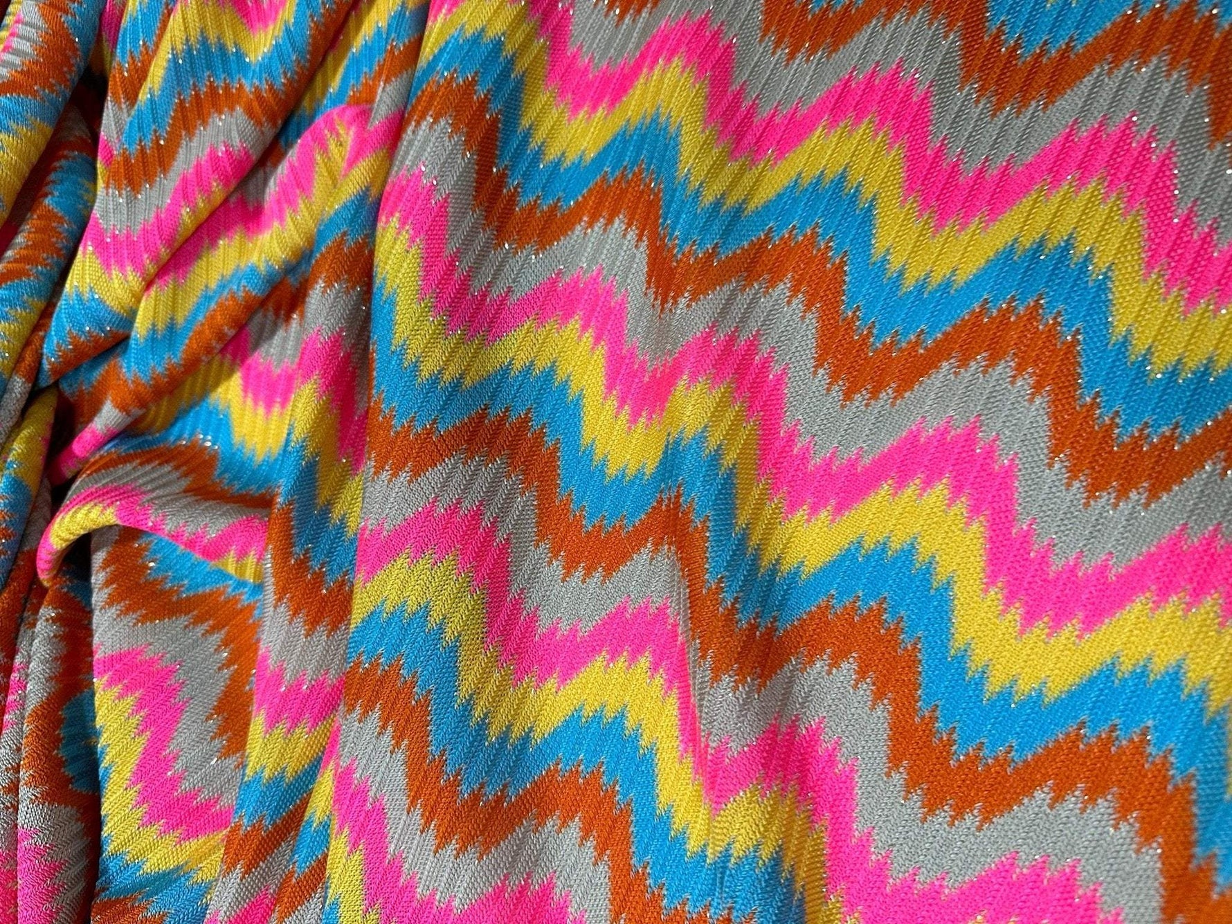 Luxury zigzag knit jersey fabric with pink, blue, yellow, and orange chevron pattern