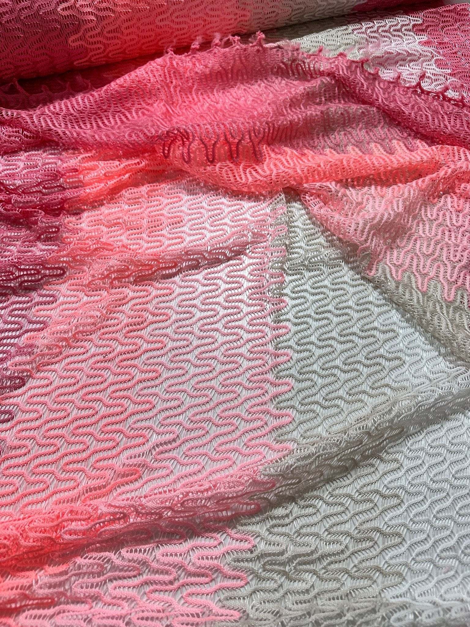 Chevron zigzag knit jersey fabric in pink and white with textured pattern, ideal for sewing garments.