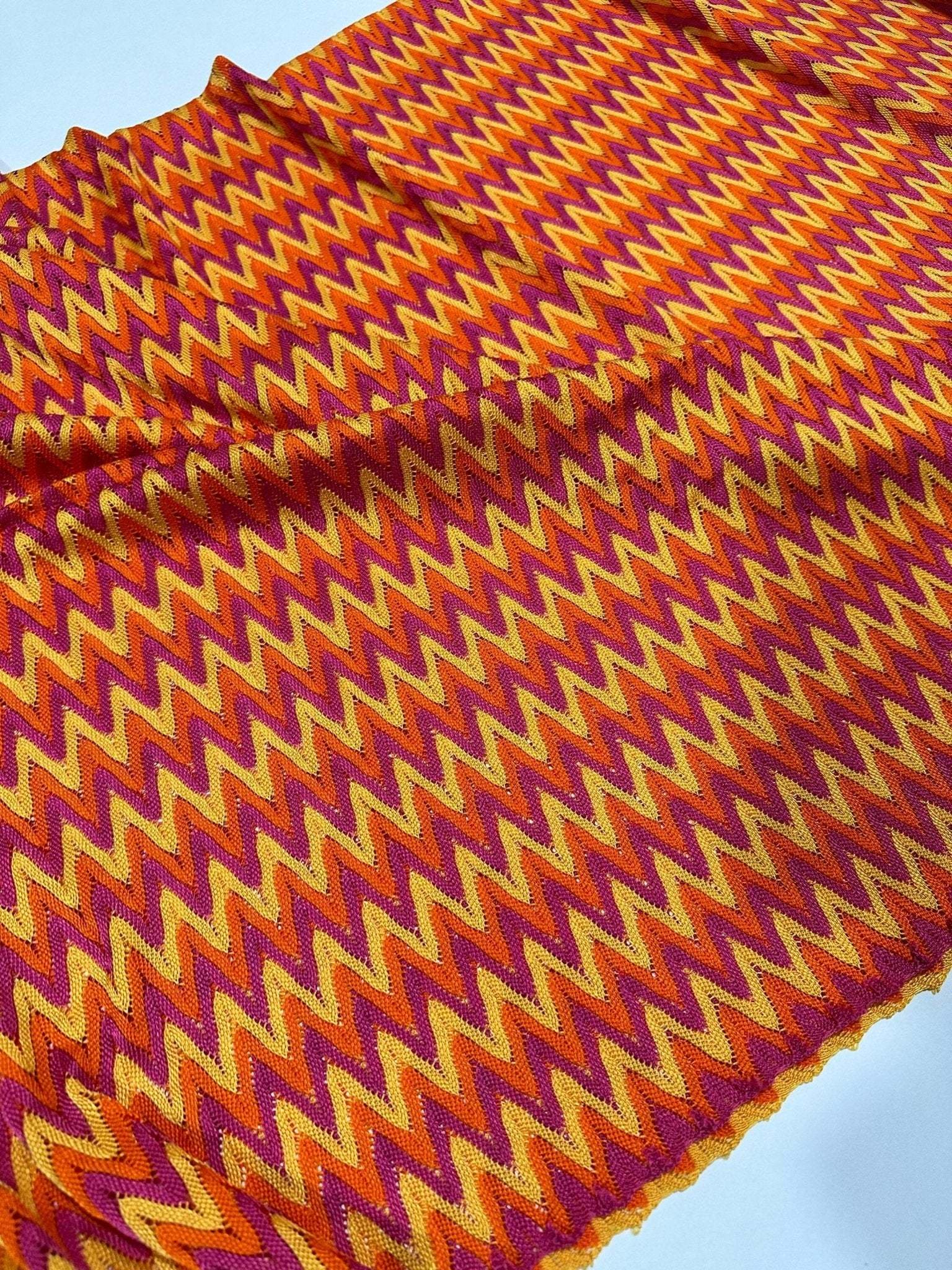 Chevron zigzag knit jersey fabric with orange, yellow, and purple zigzag pattern, 150 cm wide for fashion projects