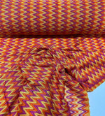 Chevron Zigzag knit jersey fabric in orange, yellow, and purple hues with a vibrant zigzag pattern.