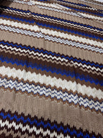 close-up of shimmer brown zigzag knit mesh fabric with blue, brown, and white zigzag patterns and elastic jersey texture